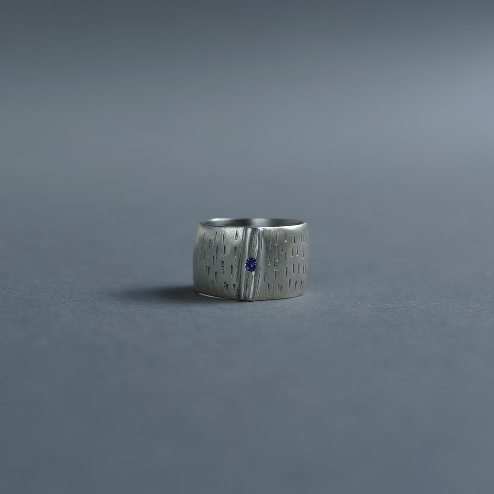 Melanie Decourcey / Silver ring with horizontal lines and small sapphire